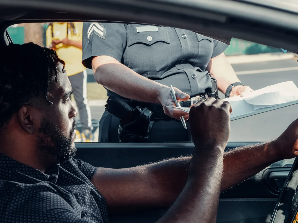 Man being given a traffic ticket by a police officer. He has so many he may loose his license and need a good traffic ticket lawyer.